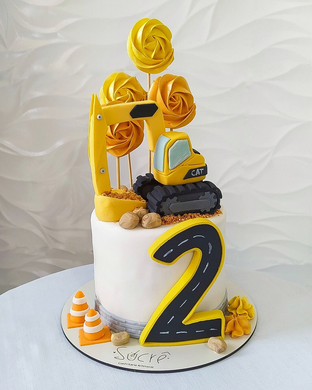 Bolo decorado com retroescavadeira modelada e pirulitos de marshmallow