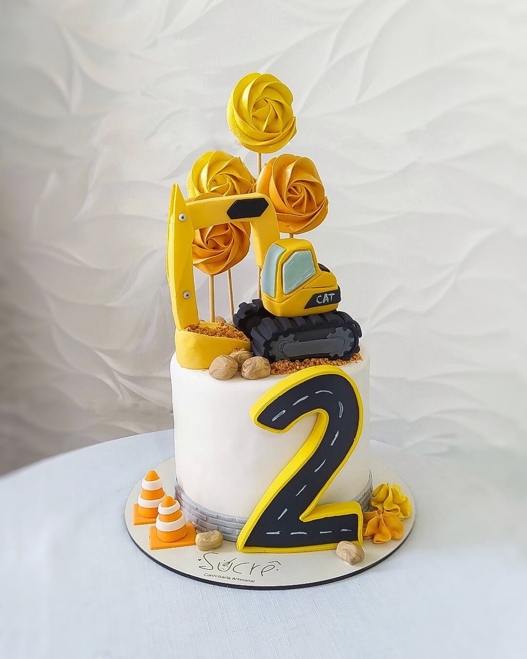 Bolo decorado com retroescavadeira modelada e pirulitos de marshmallow